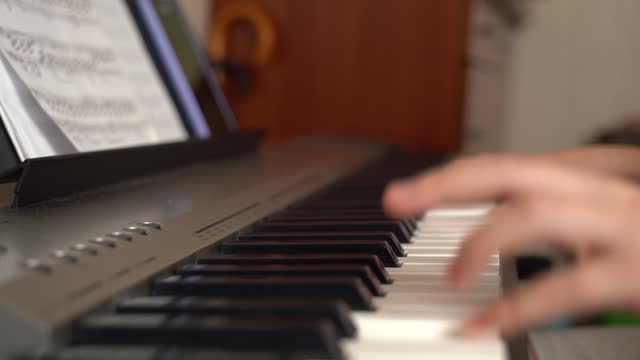 The girl is learning to play the electronic piano at home.