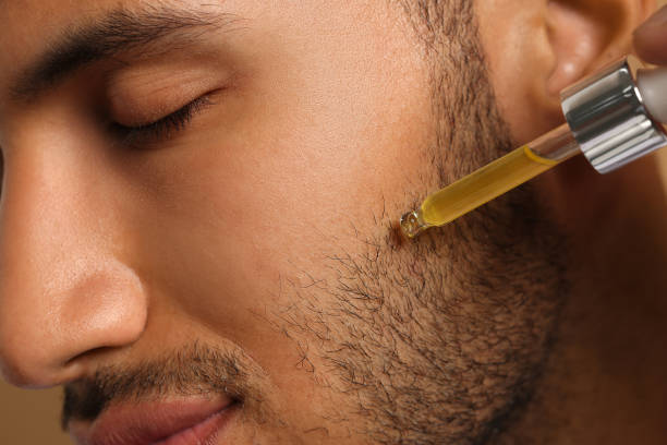 istock Handsome man applying cosmetic serum onto face, closeup 1940743088