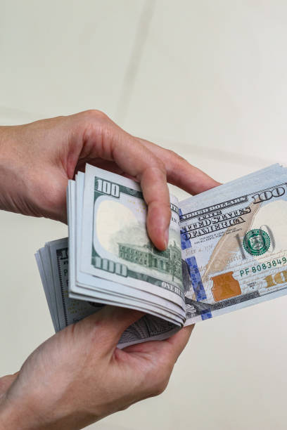 istock Close up view of hand holding US dollar banknotes. 1940756463