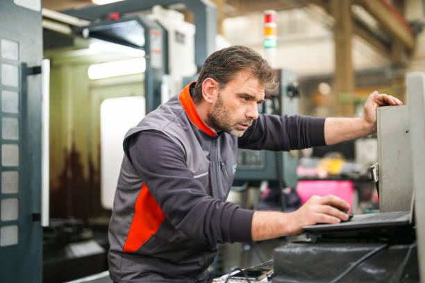 istock Male technician making designs from laptop in front of CNC machine in industry 1940760164