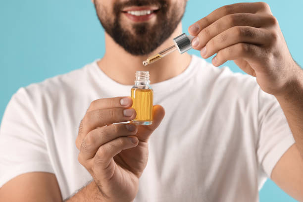 istock Man with cosmetic serum in hands on light blue background, closeup 1940768064