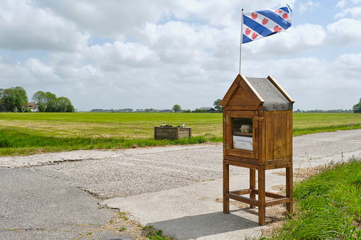 Cabinet with Frisian flag on top at a farm in Friesland The Netherlands on a sunny summer day. Free-range eggs for sale in Frisian language.