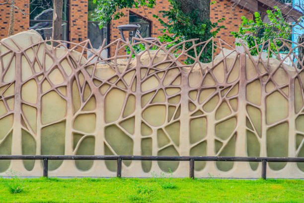 istock Vertical wall garden that uses green artificial leaf, Beautiful background. a concrete fence made to look like an artificial forest. Texture of tree trunks and branches 1940774375