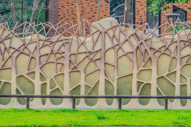 Vertical wall garden that uses green artificial leaf, Beautiful background. a concrete fence made to look like an artificial forest. Texture of tree trunks and branches