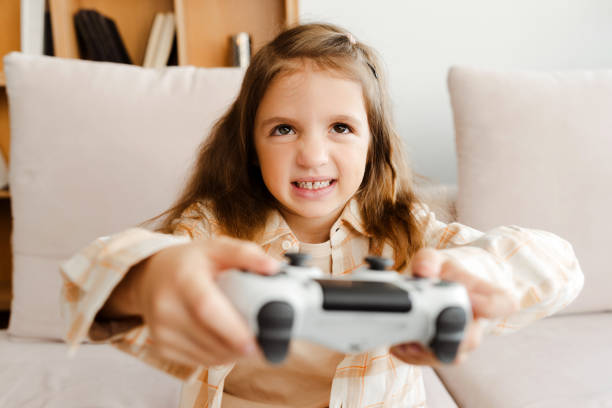 istock Angry little girl holding game console playing video games while sitting on comfortable sofa 1940780107