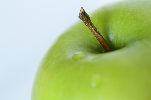 The stem and top part of a green apple.