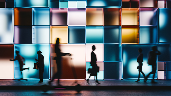 Night render of a building made of glowing cubes, people walking past