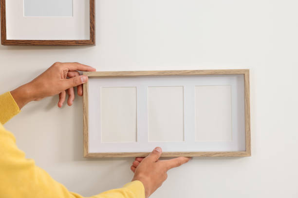 istock Young man hanging picture frames on white wall indoors, closeup. Space for text 1940792097