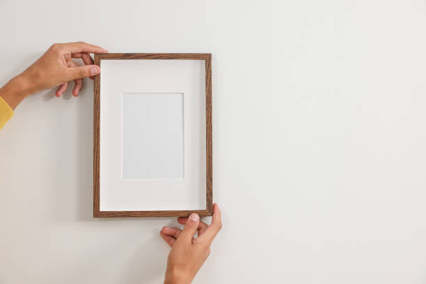 istock Young man hanging picture frame on white wall indoors, closeup. Space for text 1940792100