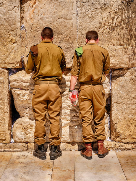 Jerusalem, Israel - June 6, 2023: Two anonymous Israeli soldiers in uniform pray at the Western Wall of the Kotel in the Old City of Jerusalem.