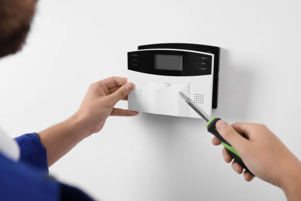 istock Man installing home security alarm system on white wall indoors, closeup 1940845046