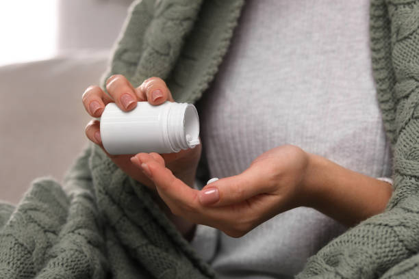 istock Woman pouring antidepressants from bottle on light background, closeup 1940930774