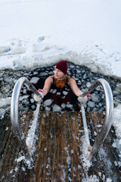 Stockholm, Sweden Stockholm, Sweden Jan 5, 2024 A young woman bathing in an icy lake in the winter with hat and mittens. just do it stock pictures, royalty-free photos & images
