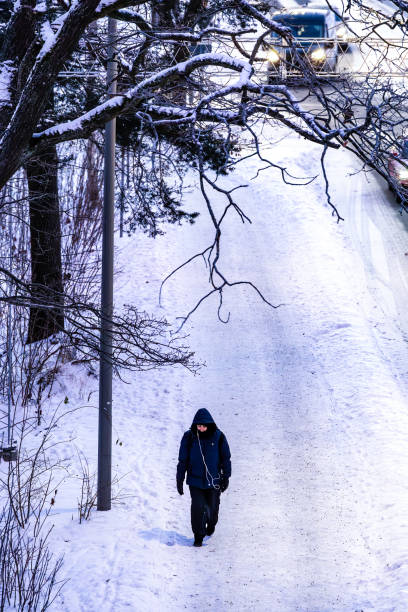 Stockholm, Sweden Jan 8, 2024 A person walking alone on a snowy sidewalk in the Vastertorp suburb.