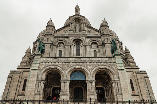 France, Paris - Jan 02, 2024 - The main entrance of the Roman Catholic church SacrÃ©-Coeur Basilica in Montmartre with the bronze statues of Joan of Arc and Louis IX on either side, Romano-Byzantine architecture constructed in travertine. Space for text, Selective focus.