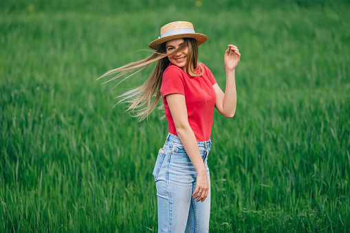 carefree adorable woman in a field with walks on the grass waving her hair.
