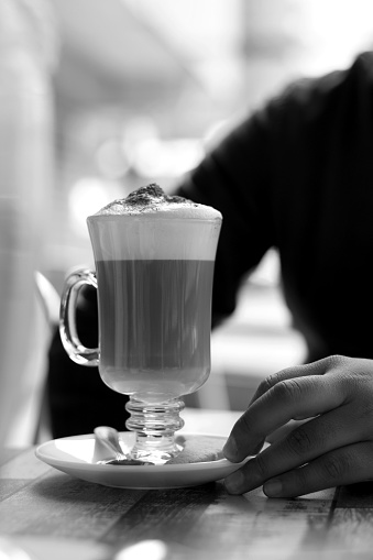 cappuccino coffee in a glass cup on a restaurant table, black and white photography