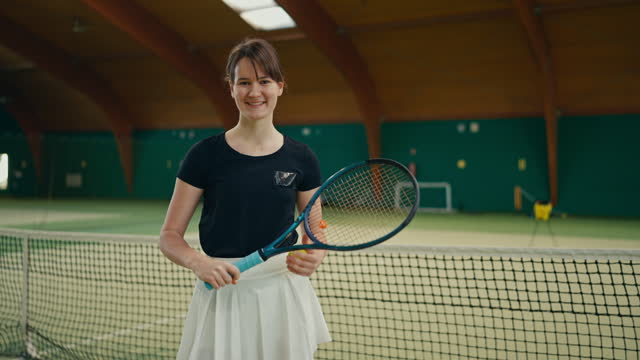SLO MO Portrait of Smiling Young Female Player Bouncing Ball on Tennis Racket in Sports Club