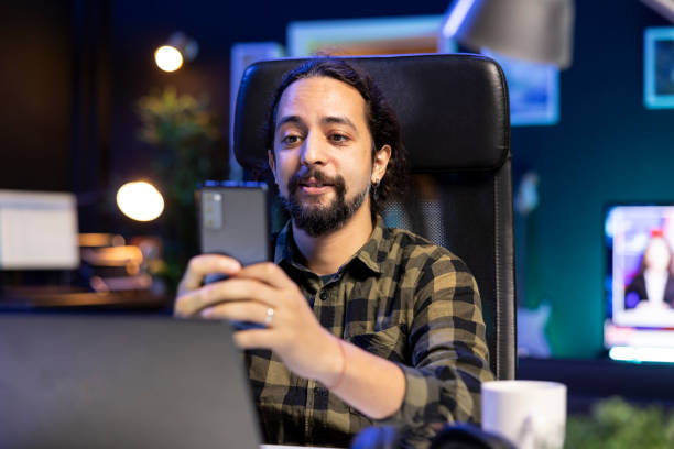 istock Man holds phone in front of laptop 1941074958