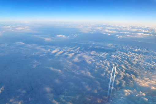 The contrails from a jet airplane as it streaks above the clouds on the way to its destination.