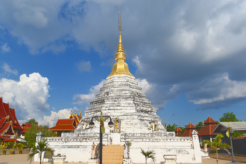 Wat Luang, Phrae, Thailand, large octagonal chedi, white chedi, top part gilded, stands on a square base, fourteenth century, lanna style, statue of standing buddha in a niche, elephant sculptures, artwork, crafts, attraction, point of interest