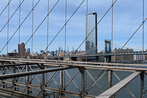 New York City, New York, USA, April 8, 2023 - The One Manhattan Square Tower with the George Washington Bridge as seen from the Brooklyn Bridge.