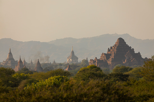 A landscape of mountains, temples and pagodas, immersed in the haze, dust and dry forest that surrounds them, in Bagan, Myanmar