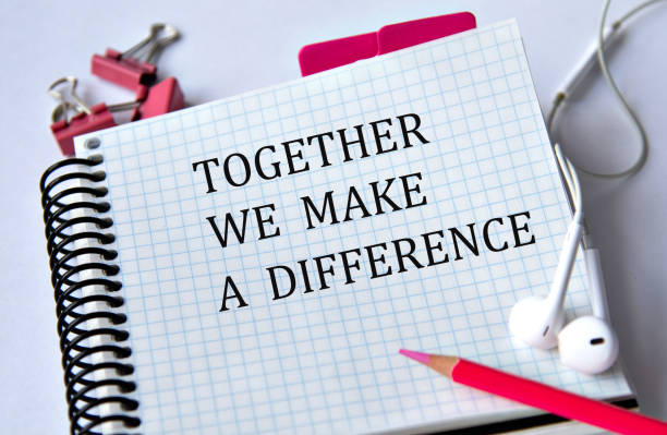 istock TOGETHER WE MAKE A DIFFERENCE - words in a white notebook on a white background with headphones and a pencil 1941168168