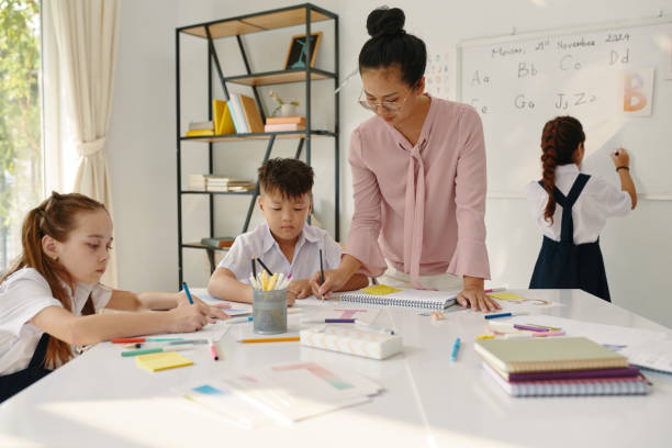 istock Teacher Helping Kids Writing Letters 1941172345