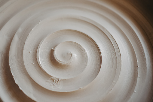 A beautiful spiral, a helical line on a clay surface. Pottery, clay texture decorated with a spiral notch. Abstract clay background Macro, top view