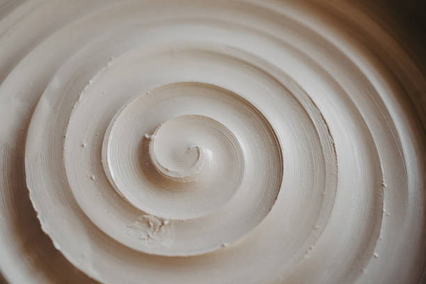 A beautiful spiral, a helical line on a clay surface A beautiful spiral, a helical line on a clay surface. Pottery, clay texture decorated with a spiral notch. Abstract clay background Macro, top view helical stock pictures, royalty-free photos & images