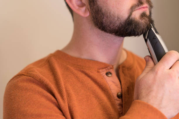 Man trims his beard with an electric trimmer.