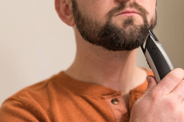 istock Man trims his beard with an electric trimmer. 1941216441
