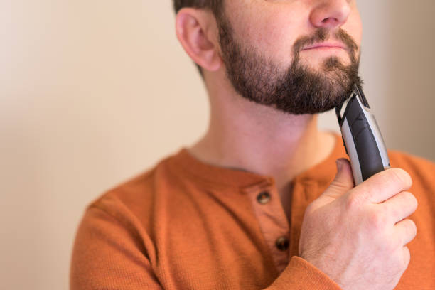 istock Man trims his beard with an electric trimmer. 1941220051