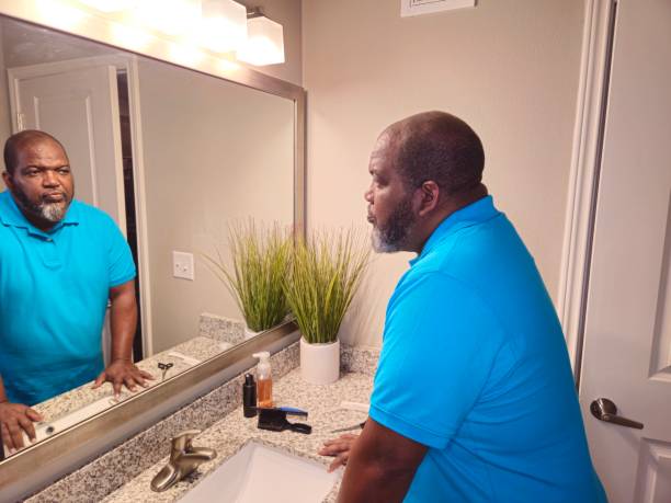 istock Black Male Looking At His Reflection In Bathroom Mirror 1941260670