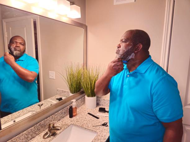 istock Black Male Shaving While Seeing His Reflection In Mirror 1941260758
