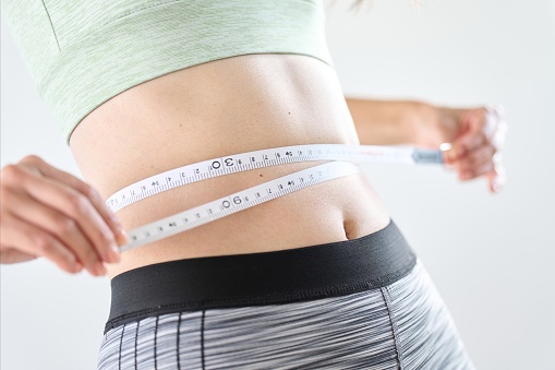 A woman measuring her stomach circumference with a tape measure