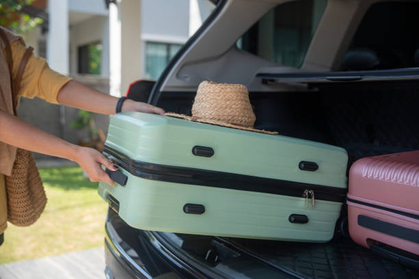 istock woman packing her suitcase into the car trunk. 1941289454