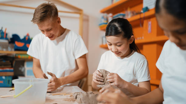 istock Boy modeling bowl of clay while cute asian girl working on dough. Edification. 1941290071
