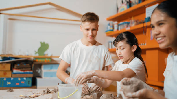 istock Boy modeling bowl of clay while cute asian girl working on dough. Edification. 1941292810