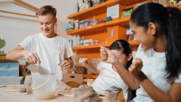 istock Student playing with friend while put the clay on shirt at class. Edification. 1941293868