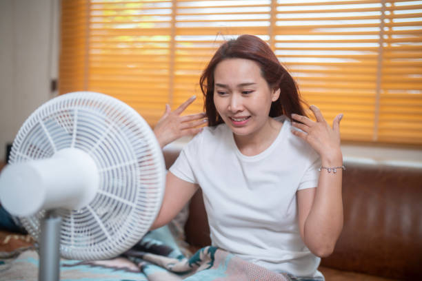 istock Sweating Asian girl cooling herself with big fan 1941309224