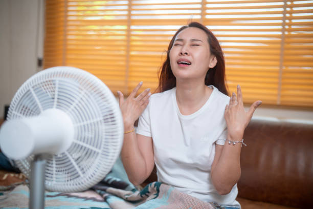 istock Sweating Asian girl cooling herself with big fan 1941309226