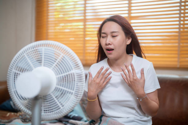 istock Sweating Asian girl cooling herself with big fan 1941309229