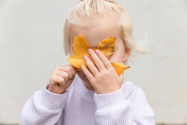 Blonde girl holding leaf over face