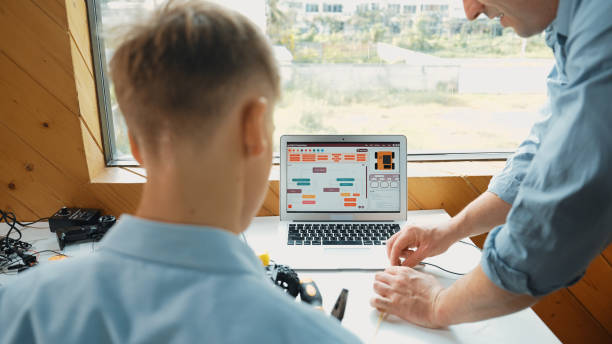 istock Closeup of teacher picking wires while boy looking at instructor.. Edification. 1941314983