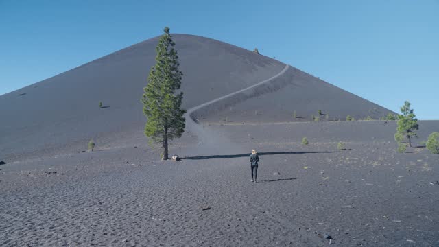 Woman hiker approaching  Cinder Cone Trail winding up mountain in Lassen National Park