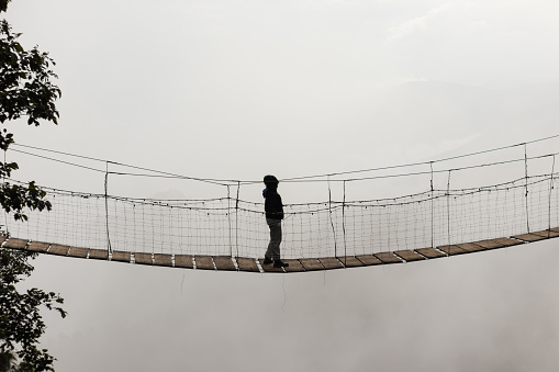 A lone person stands on a high bridge in the mountains of Fukushima Prefecture watching the sunrise.