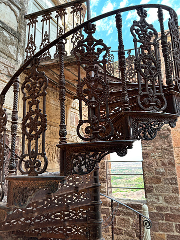 Jodhpur, Rajasthan, India - April, 11 2023: Stock photo showing view of a weathered and rusty iron spiral ornate staircase.