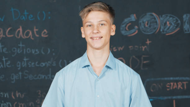 istock Smiling teenager looking at camera while standing at blackboard. Edification. 1941350044